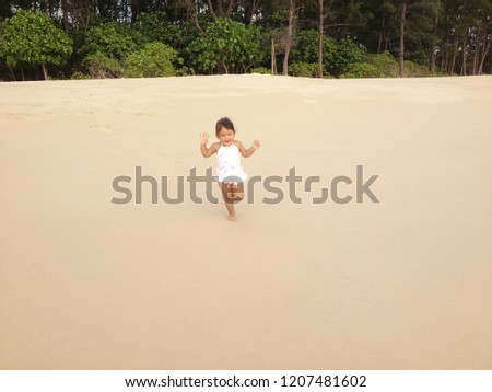 A little asian girl running on tropical beach.