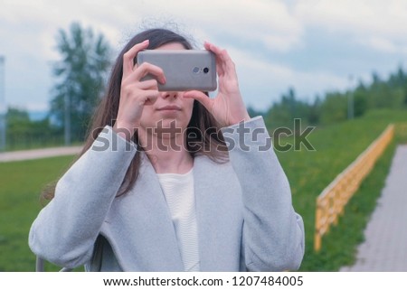 Young woman shoots a photo and video on a mobile phone on the Playground.