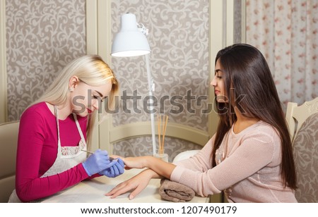 Pretty young woman doing manicure in salon. Beauty concept. Royalty-Free Stock Photo #1207490179