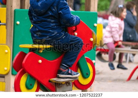 child having fun on the playground on a cold autumn day