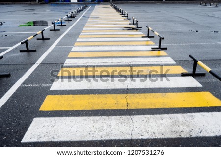 Pedestrian crossing near the parking lots, white and yellow stripes.