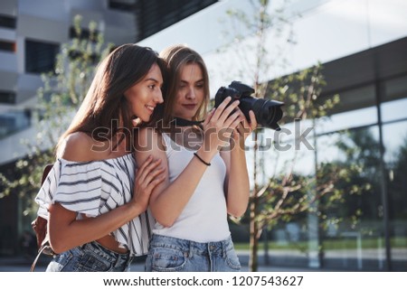 Two pretty pretty friends of the girl with the camera take photos together and walk in the city.
