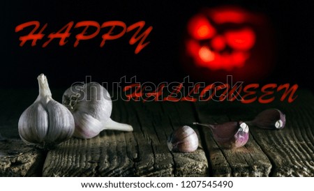 Halloween celebration. Garlic closeup and Jack's lantern. Black background.