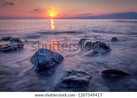 Long exposed photo of stones in the water of Mediterranean sea at sunrise. Crete, Greece