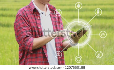 Smart farming, using modern technologies in agriculture. Man agronomist farmer with digital tablet computer in field using apps and internet of things(IOT) in production and agricultural research Royalty-Free Stock Photo #1207550188