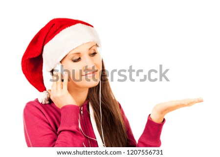 Attractive smiling young girl dressed in Santa's hat listening the music by headphones. Christmas and New Year advertising concept. Detailed studio shoot isolated on abstract blurred white background
