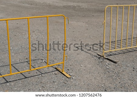 temporary yellow fence or barrier on a gravel car park in bright sunlight