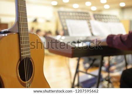 A person playing an electric piano A guitar set up behind