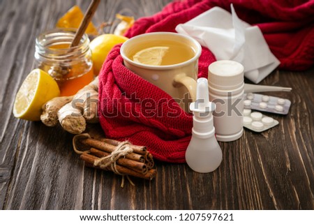 Medical care concept - ginger honey and lemon tea with drugs, pills and spray on wood background Royalty-Free Stock Photo #1207597621