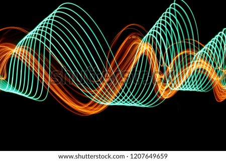 Long exposure, light painting photography.  Green and vibrant metallic yellow gold, parallel lines of vibrant color, curving and wavy lines against a black background