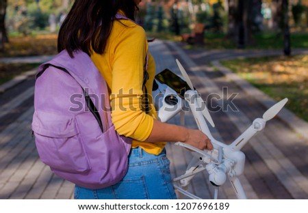 closeup asian girl with backpack holding copter in autumn park