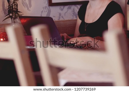 Female freelancer’s hands typing on laptop keyboard while sitting in coffee shop indoors