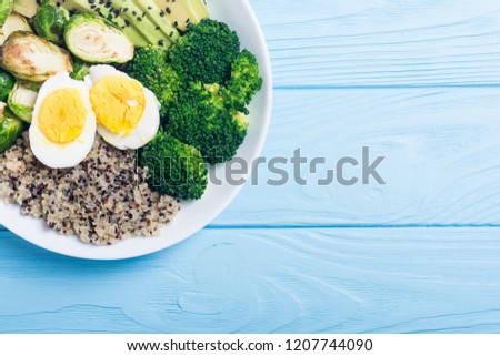 Buddha bowl with quinoa , eggs , avocado , brussels sprouts and broccoli . Food vegan salad on wooden backgground
