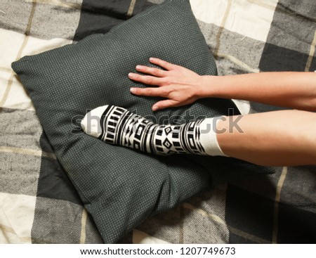 Women's legs in beautiful socks with black geometric authentic ornament. Legs lie on a green pillow.