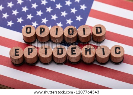 Elevated View Of Opioid Epidemic Text On Wooden Cork Over American Flag Royalty-Free Stock Photo #1207764343