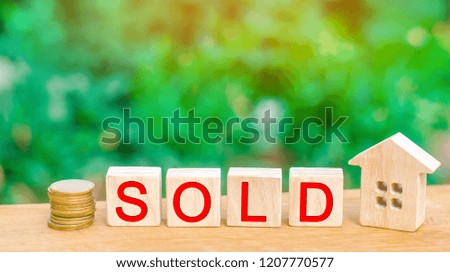 wooden house and coins with the inscription "sold". sale of property, home, real estate. affordable housing.
