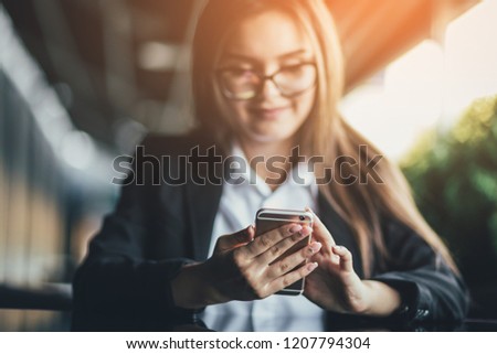 Business woman using smart phone at outdoor cafe. Sunlights background