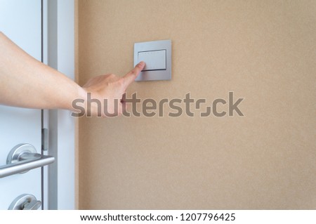 Man use index finger on left hand switch on or off the light or push doorbell switch on the wall