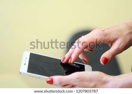 Female hands with red nails are holding a smartphone