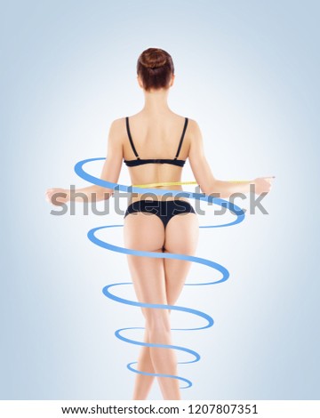 Fit, healthy and sporty woman in black swimsuit isolated on white. Beautiful girl measuring her body. Sport, fitness, diet, weight loss and healthcare concept.