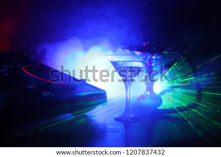 Glass with martini with olive inside on dj controller in night club. Dj Console with club drink at music party in nightclub with stylish oriental shisha