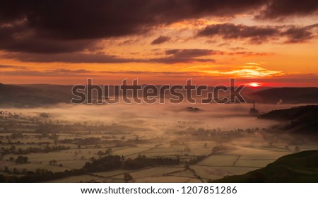 Sunrise over misty valley with works chimney.