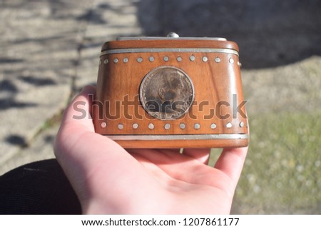 Hand holding vintage tobacco box made of wood with old coin on it