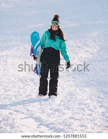 Leisure, sport concept - amateur snowboarder go with her board on snowy slope