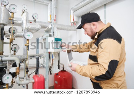 heating engineer or plumber inspector in boiler room taking readouts or adjusting meter Royalty-Free Stock Photo #1207893946