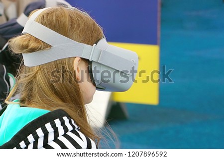 Cute little child girl playing game in virtual reality glasses.Girl in glasses of cyberspace, spending time in virtual reality.                               