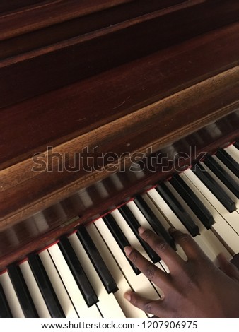 An African American woman playing a brown piano