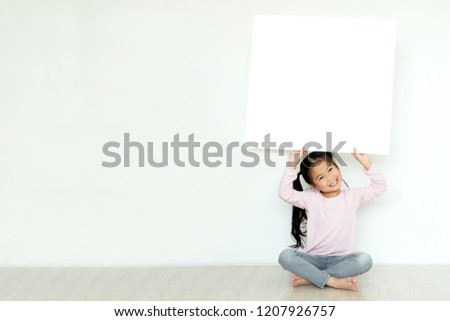 Young little asian girl or kid enjoy holding empty white placard board for media banner, business content presentation, mock up blank sign for message with positive and fun in creative design concept.