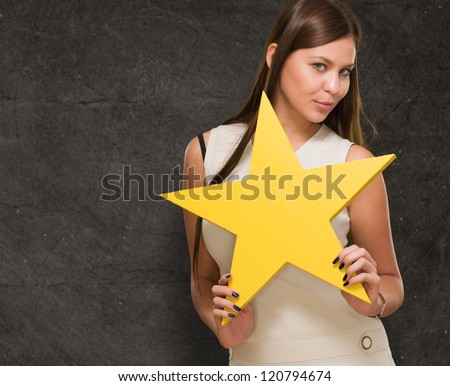 Portrait Of Young Woman Holding Yellow Star against a grunge wall