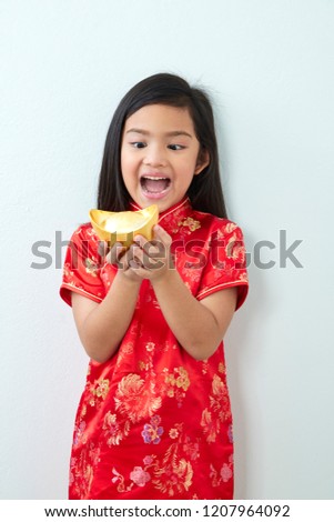 Girl child 8 years in traditional Chinese dress  New year 2019 with holding a gold ingot standing on white wall background
