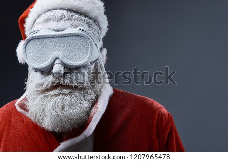 Close up portrait of bearded old man in Santa costume covered with snow. Copy space on right side