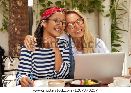 Happy students have homosexual relationships, celebrate successful passed project work, check marks online, waits for updates installation, write in notepad, drink latte, embrace each other.