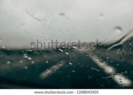 Rain falls on vehicle windshield.