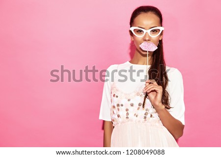 Portrait of  funny woman in paper glasses and big lips on stick. Smart and Beauty concept. Joyful young model ready for party. Girl isolated on pink background. Positive female