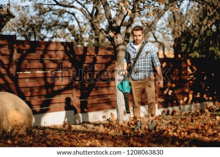 Professional gardener working with leaf blower, vacuum and industrial tools