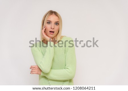 Photo portrait of a beautiful blonde girl talking on a white background with different emotions. She is standing right in front of the camera, smiling and looking happy.