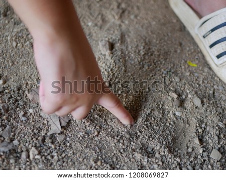 Close up of baby hand drawing on a sandy ground