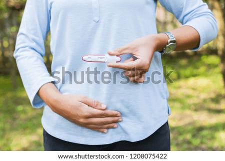 Close up picture of future mommy holding her belly and positive pregnancy test