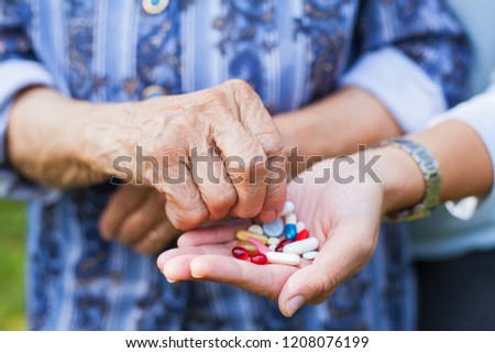 Close up picture of wrinkled elderly hand and a handful of medication and vitamins