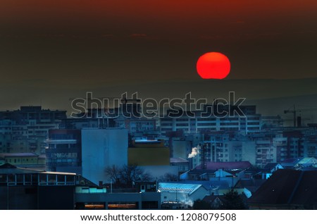 Sunrise over a city with red circle sun above. Cityscape sunrise
