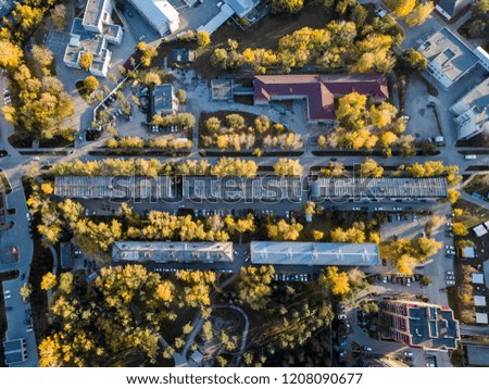 Aerial view of a large number of residential buildings on the outskirts of the city on an autumn day during the Indian summer with the road and cars