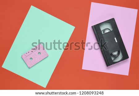 Audio cassette and video cassette on a colored paper background. Retro entertainment technology from the 80s. Top view. Minimalism. Copy space

