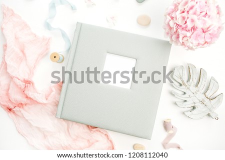 Family or wedding photo album with blank space for text, hydrangea flower bouquet, pink blanket, decoration on white background. Flat lay, top view.