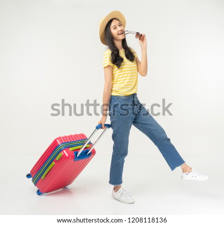 Beautiful young woman smiling and pulling pink color luggage isolated on white background.Woman going to summer vacation.Travel trip funny.
