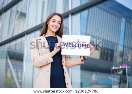 Businesswoman with long Hair Holding a sign Board with a Welcome has Airport Background.