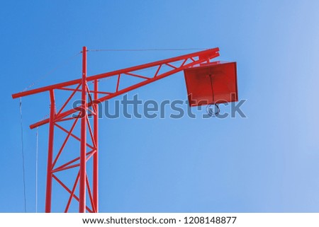 Modern red stylish street lamp of urban lighting in style of construction crane against blue sky. Concept object is under construction, banner